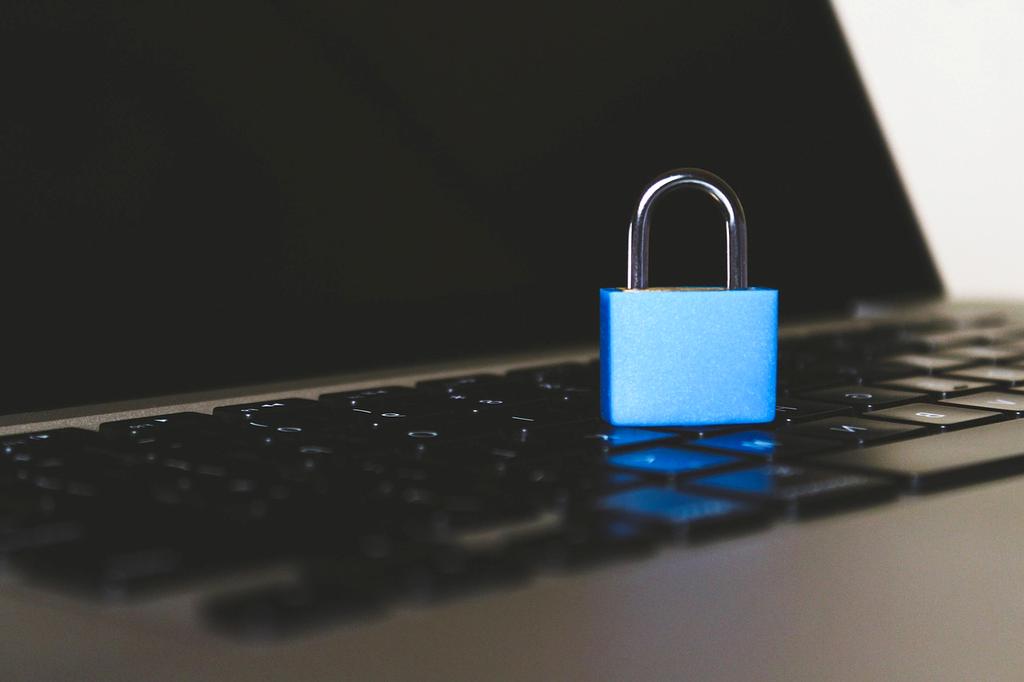 Zamknięta kłódka na tle laptopa symbolizująca bezpieczeństwo cyfrowe